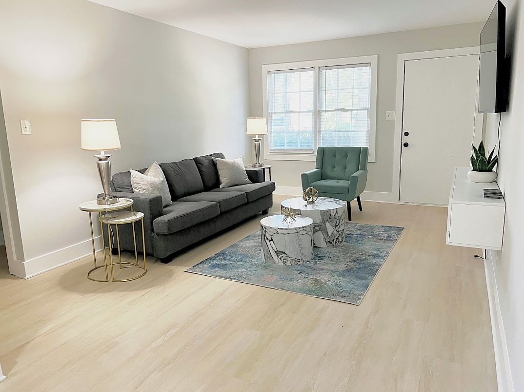A living room with a grey sofa, two side tables, a green armchair, and a marble coffee table.