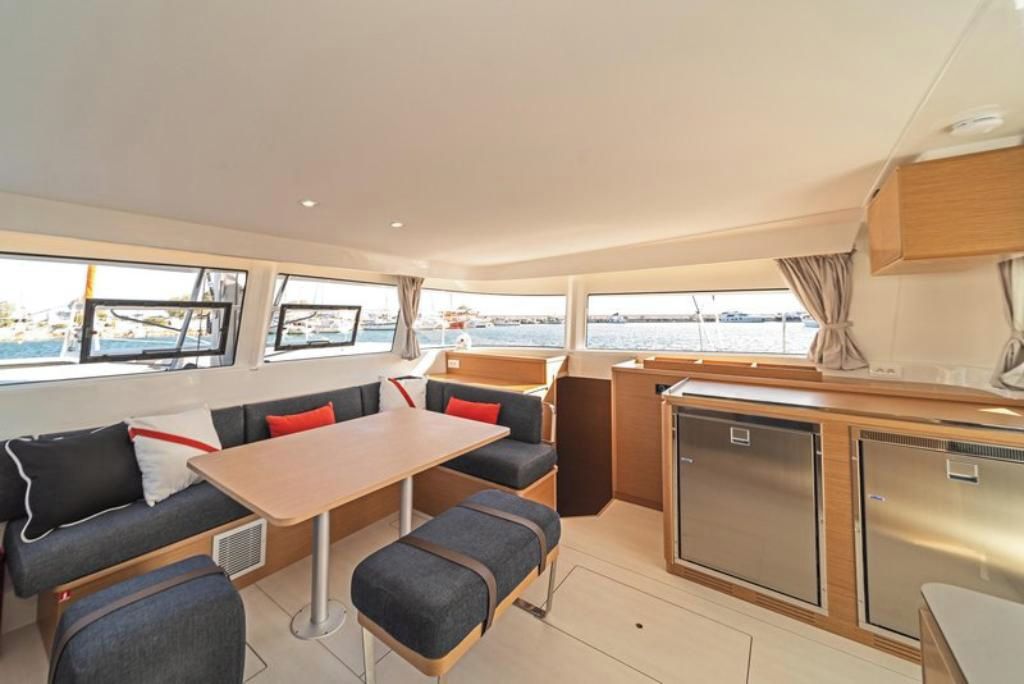 Interior de barco compacto con comedor, asientos y cocina pequeña.