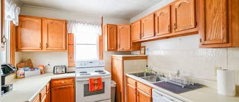 Una cocina con armarios de madera, una estufa blanca, un lavamanos y un ventilador de techo.