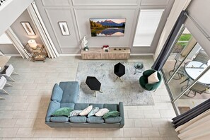 A modern living room with a sectional sofa, a coffee table, and a TV mounted on the wall. - Perfect Family Escape, Pool, Themed Rooms (Kissimmee)
