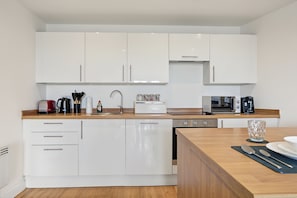A modern kitchen with white cabinets, stainless steel appliances, and a wooden countertop. - City Centre 2BR • Workspace • Gym • Parking Spot (Manchester)