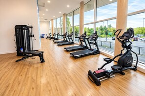 Ein Fitnessstudio mit Laufbändern, Kraftgeräten und einer Bank.
