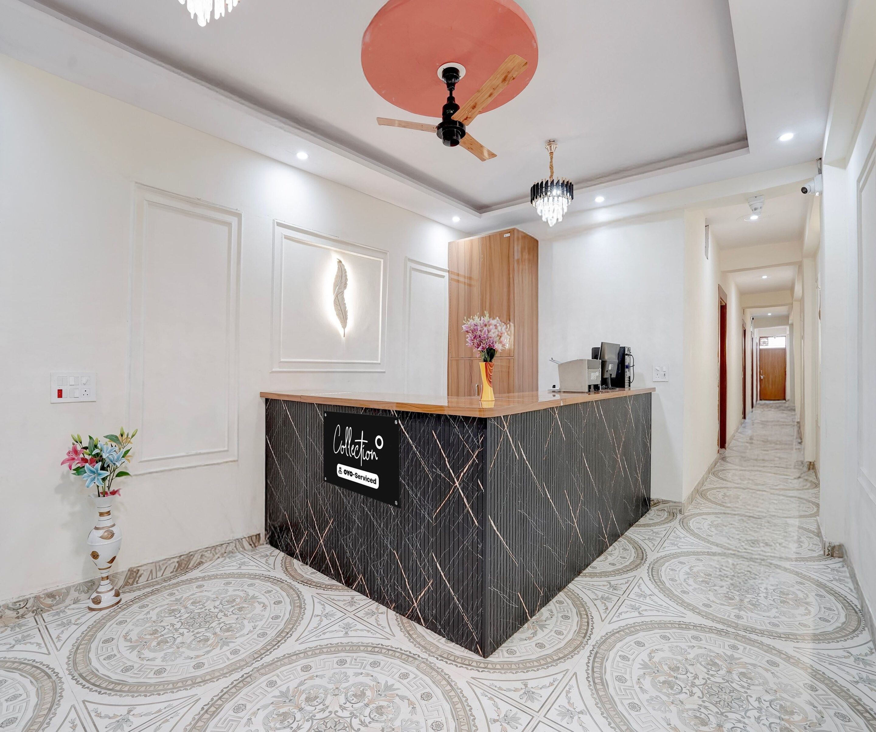 Un área de recepción con diseño moderno, que incluye un mostrador de recepción, un ventilador de techo y piso con diseño estampado.
