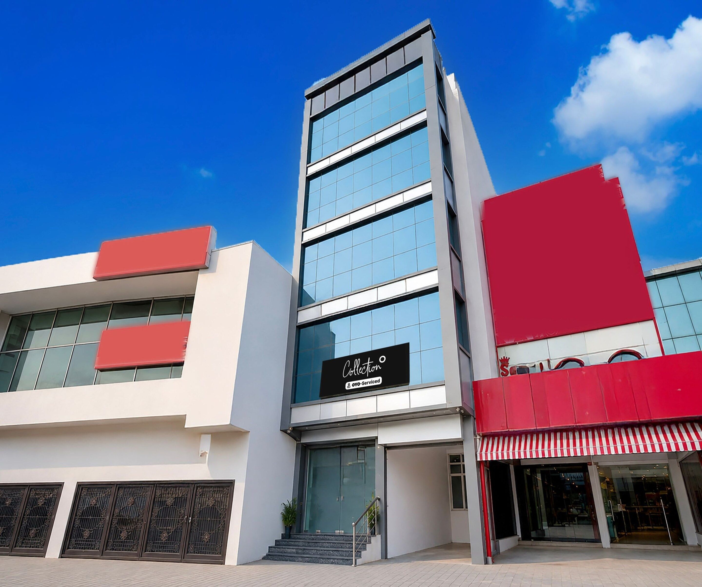 A modern building with a glass facade, a sign reading 'Collection,' and a red awning.