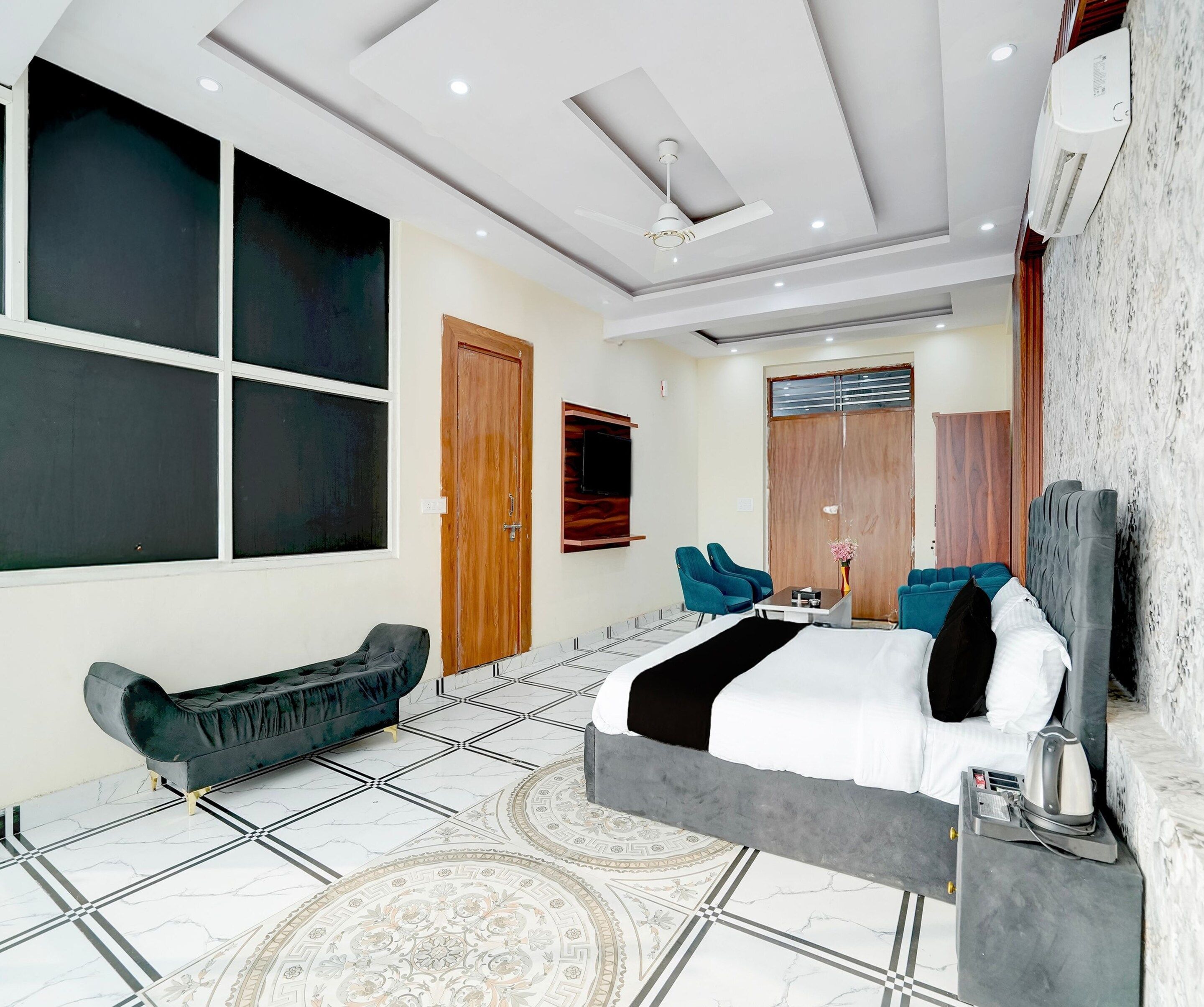 A modern bedroom with a bed, a sofa, a TV, and a ceiling fan.