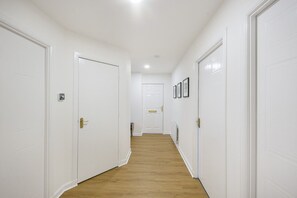 Un pasillo con puertas blancas, piso de madera y un radiador en la pared.