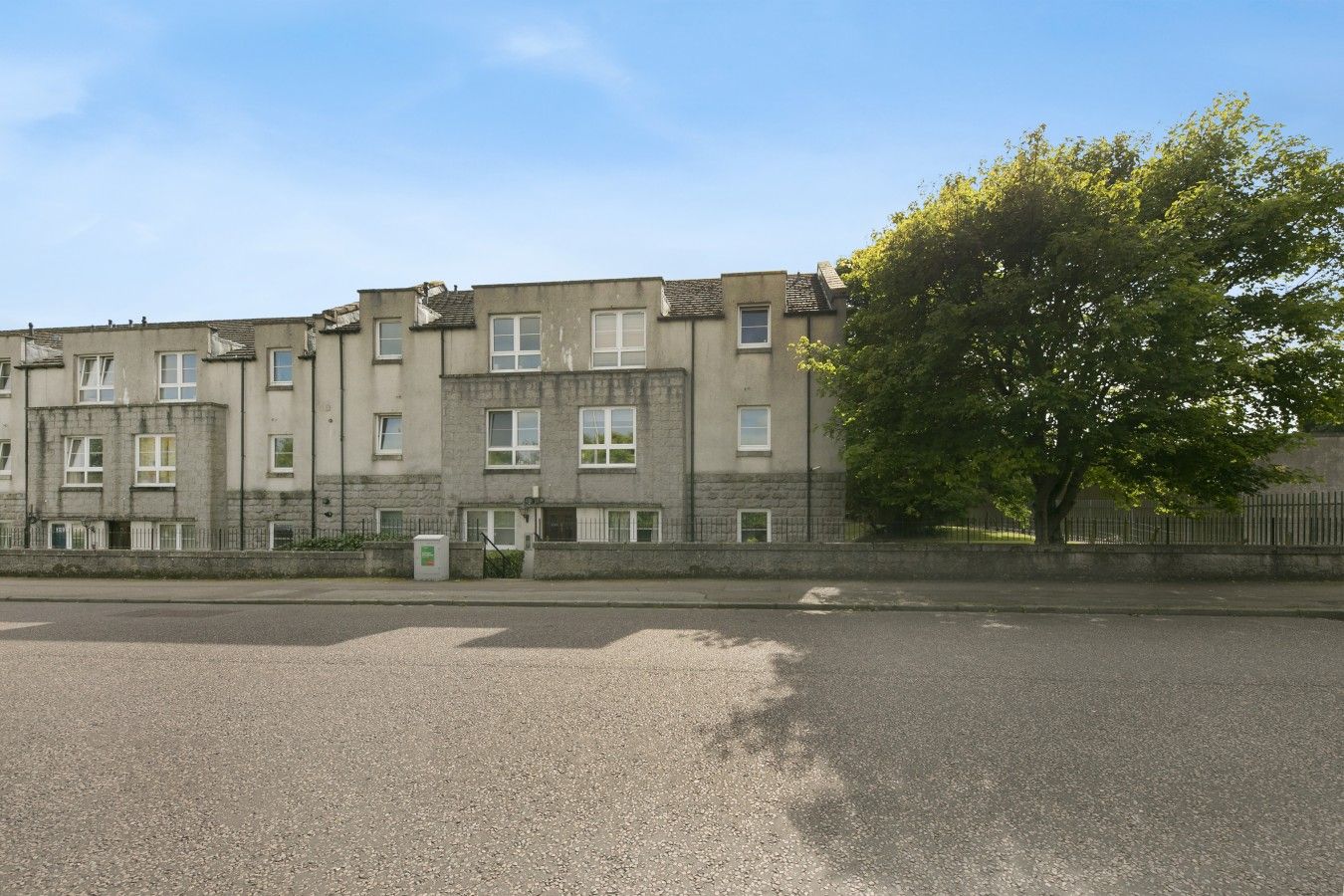 A row of multi-story residential buildings with a paved street in front.