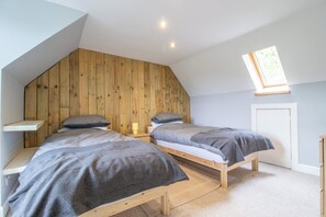 Ein Schlafzimmer mit zwei Betten, Holzwandverkleidung, einem Oberlicht und einem kleinen Fenster.