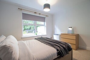 Una camera da letto con un letto, un comodino, tende alla finestra e una lampada a soffitto.