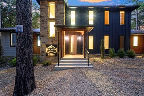 A two-story house with a stone facade, a front porch, and a driveway.