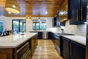 A modern kitchen with wooden flooring, dark cabinetry, and a central island.