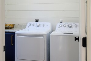 A laundry room with two white front-loading washing machines and a blue cabinet. - Resort Pool & Hot Tub | Arcade + Bunk Room (Broken Bow)