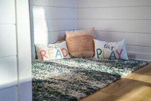 A corner of a room with a white wall, a textured rug, and three pillows with motivational phrases. - Resort Pool & Hot Tub | Arcade + Bunk Room (Broken Bow)