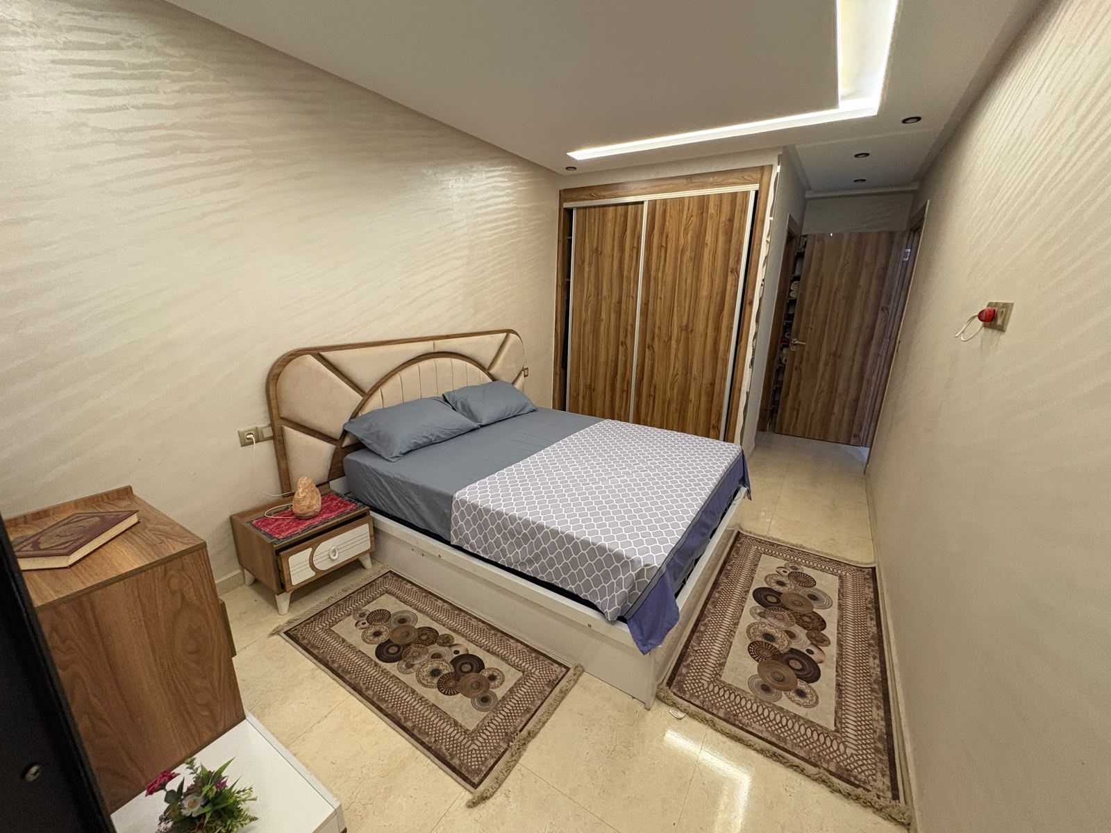 A bedroom with a bed, bedside tables, a wardrobe, and a small desk.