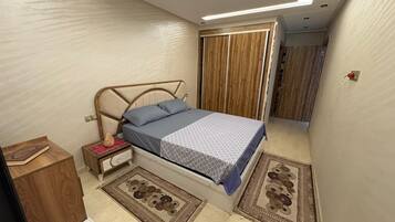 A bedroom with a bed, bedside tables, a wardrobe, and a small desk.