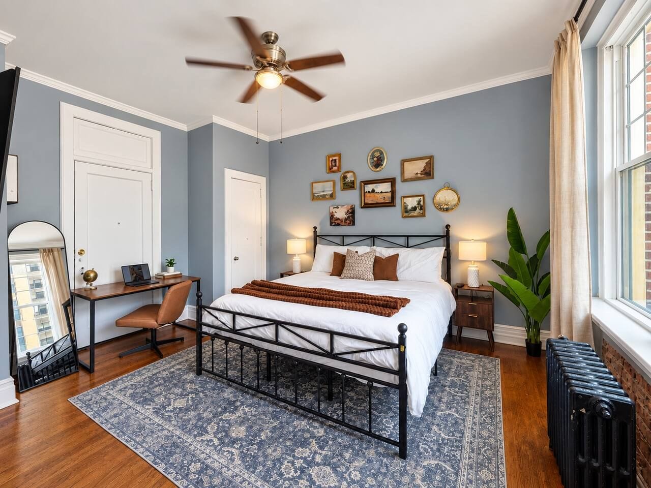 A bedroom with a bed, desk, chair, and a radiator.