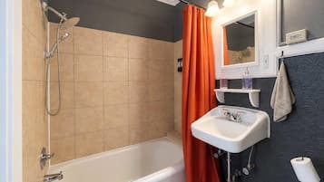 Ein Badezimmer mit einer Badewanne, einer Dusche und einem Waschbecken mit Spiegel darüber.