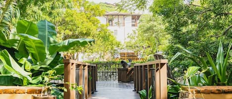 A wooden pathway leading to a building surrounded by lush greenery.
