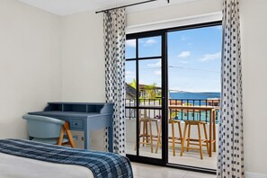 Un dormitorio con cama, escritorio y vista a una piscina y zona de estar exterior.
