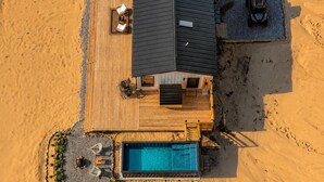 A modern house with a swimming pool, deck, and vehicles parked nearby. - Romantic Escape with Private Heated Pool & Sauna (Fife Lake)