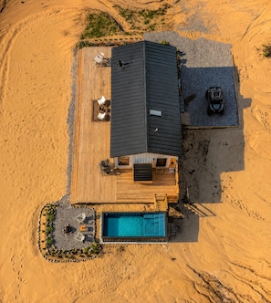 A modern house with a swimming pool, deck, and vehicles parked nearby. - Romantic Escape with Private Heated Pool & Sauna (Fife Lake)