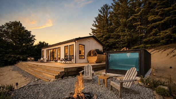 A modern house with a deck, a fire pit, and a large screen. - Romantic Escape with Private Heated Pool & Sauna (Fife Lake)