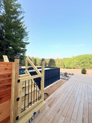 A wooden deck with a pool, a wooden gate, and a sign indicating no diving. - Romantic Escape with Private Heated Pool & Sauna (Fife Lake)