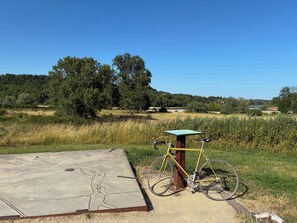 A bicycle parked next to a concrete map display in a natural setting with trees and a clear sky. - Gite des Rives du Guétin - Charming house with a garden and direct access to the canal (Cuffy)