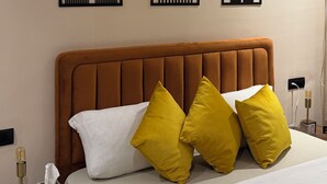 Hotellihuone, jossa on sänky, yöpöytä ja kolme seinätaideteosta.