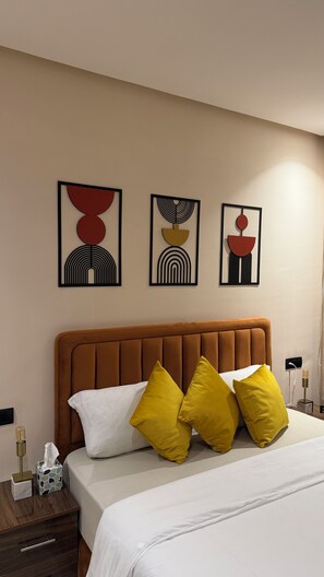 Una habitación de hotel con una cama, una mesita de noche y tres obras de arte en la pared.