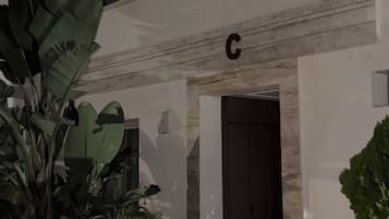 Un bâtiment avec un panneau en forme de « C », une porte et des plantes en pot.
