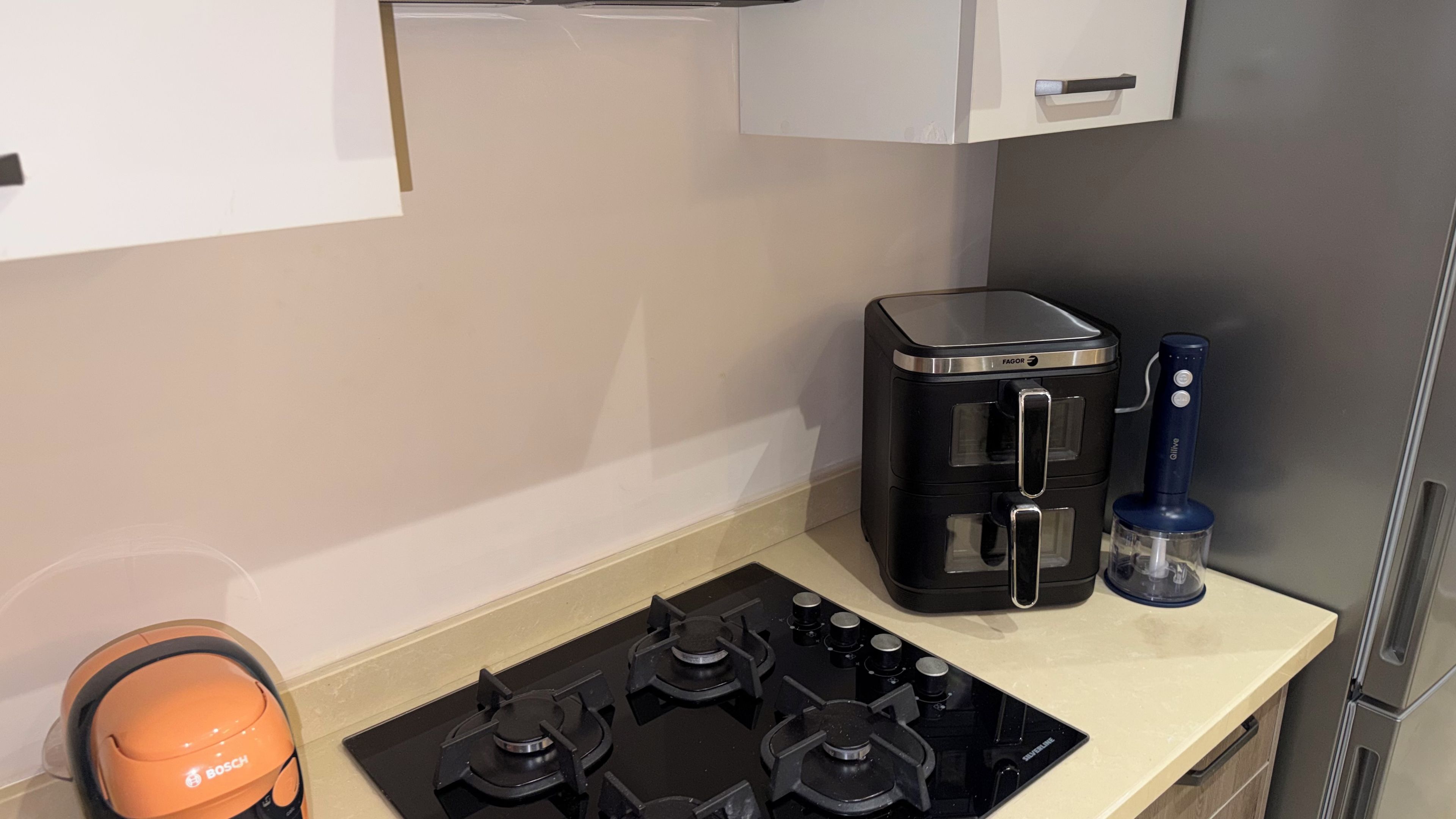 Een keuken met een gasfornuis van Bosch, een koffiezetapparaat van Fagor en een scheermesje van Gillette.