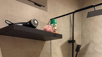 A bathroom with a shower, a toilet, and shelves with towels and a hairdryer.