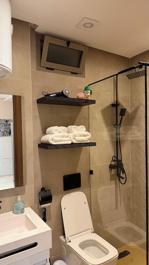 Un baño moderno con inodoro, ducha, lavamanos y espejo.
