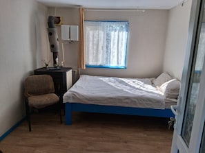 A small bedroom with a single bed, a chair, a desk with a lamp, and a window with curtains. - Terrific 3-bedroom house in enchanting Mila 23 awaits you (Mila 23)