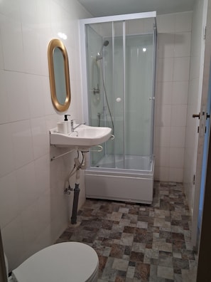 A bathroom with a glass-enclosed shower, a white sink with a gold-framed mirror, and a toilet. - Terrific 3-bedroom house in enchanting Mila 23 awaits you (Mila 23)