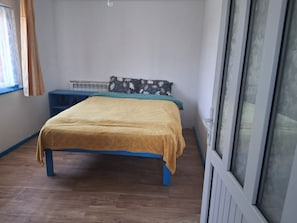 A bedroom with a bed, a blue nightstand, and a window with curtains.