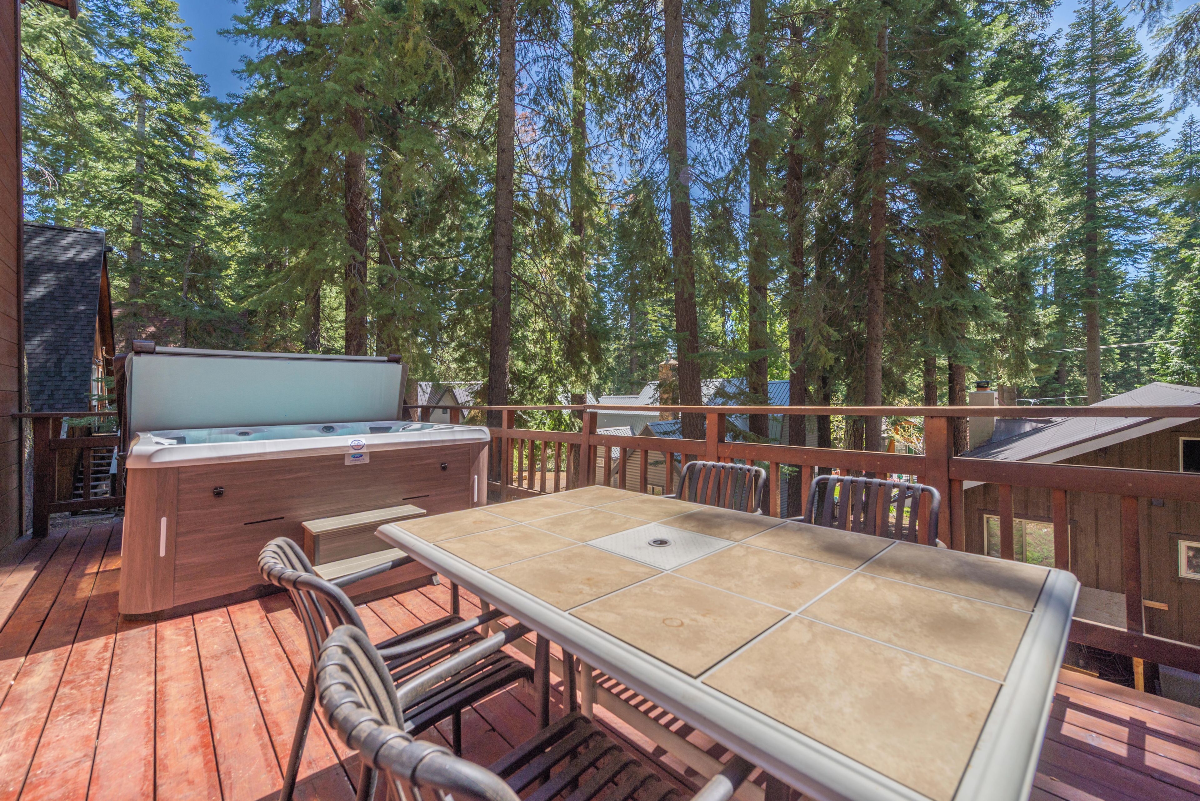 An outdoor deck with a hot tub, wooden deck, and a table with chairs.