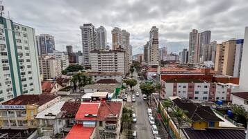 Un paysage urbain avec de hauts immeubles, une rue avec des voitures et un hôtel appelé « HÔTEL NATAL », dont le toit est rouge.