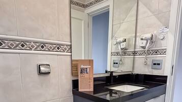 Un baño moderno con inodoro, bidé y lavamanos con espejo.