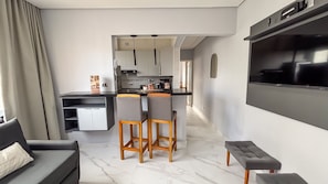 A modern kitchen with a dining area, a sofa, and a TV mounted on the wall. - SHB - Central Shopping 2 min Praia (Santos)