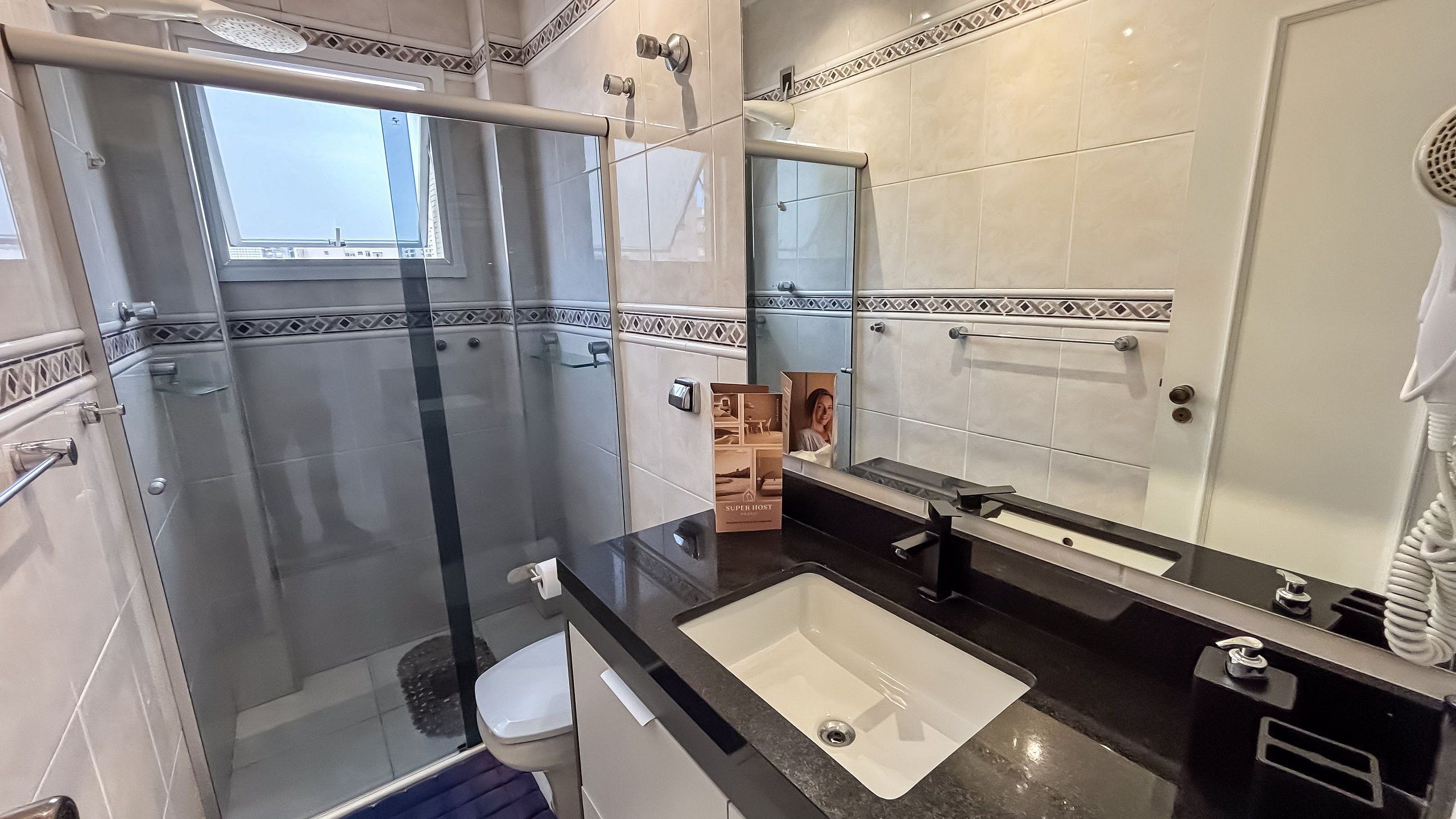 Un baño moderno con cabina de ducha de vidrio, un lavamanos blanco y un espejo grande.