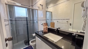 A modern bathroom with a glass shower enclosure, a sink, and a large mirror. - SHB - Central Shopping 2 min Praia (Santos)
