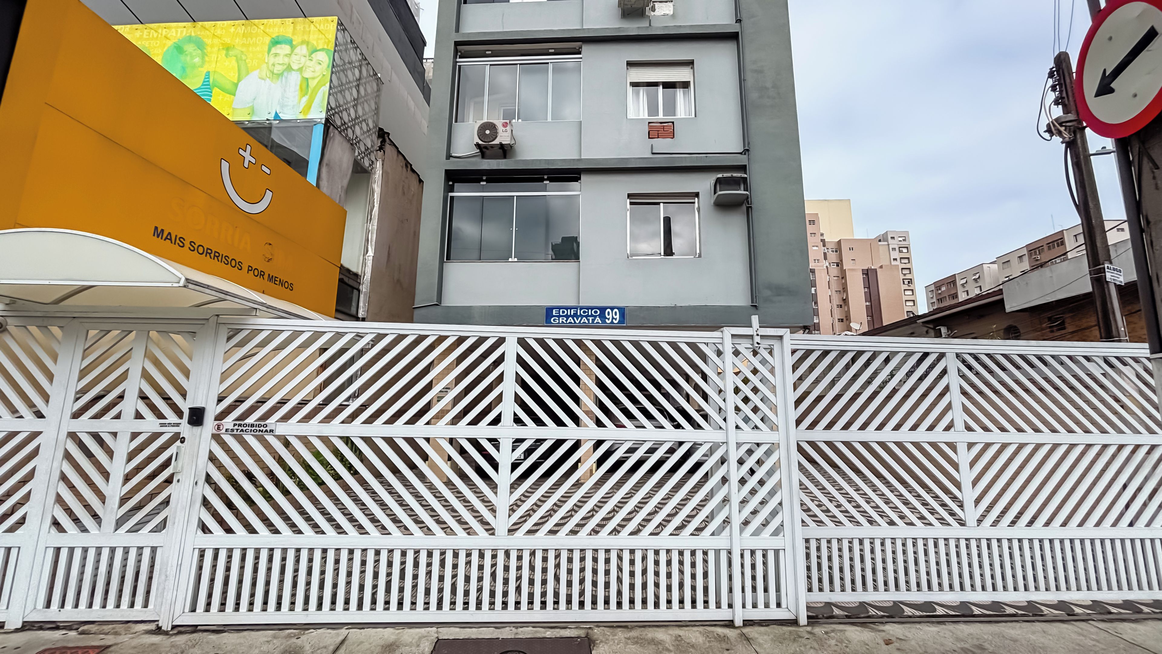 Una entrada con reja y un letrero azul que indica el número 99 del edificio.