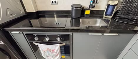 Una cocina con fregadero, cafetera y horno.