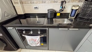 Una cocina con fregadero, cafetera y horno.