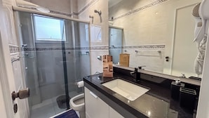 Ein modernes Badezimmer mit einer Glasdusche, einem Waschbecken und einem großen Spiegel.