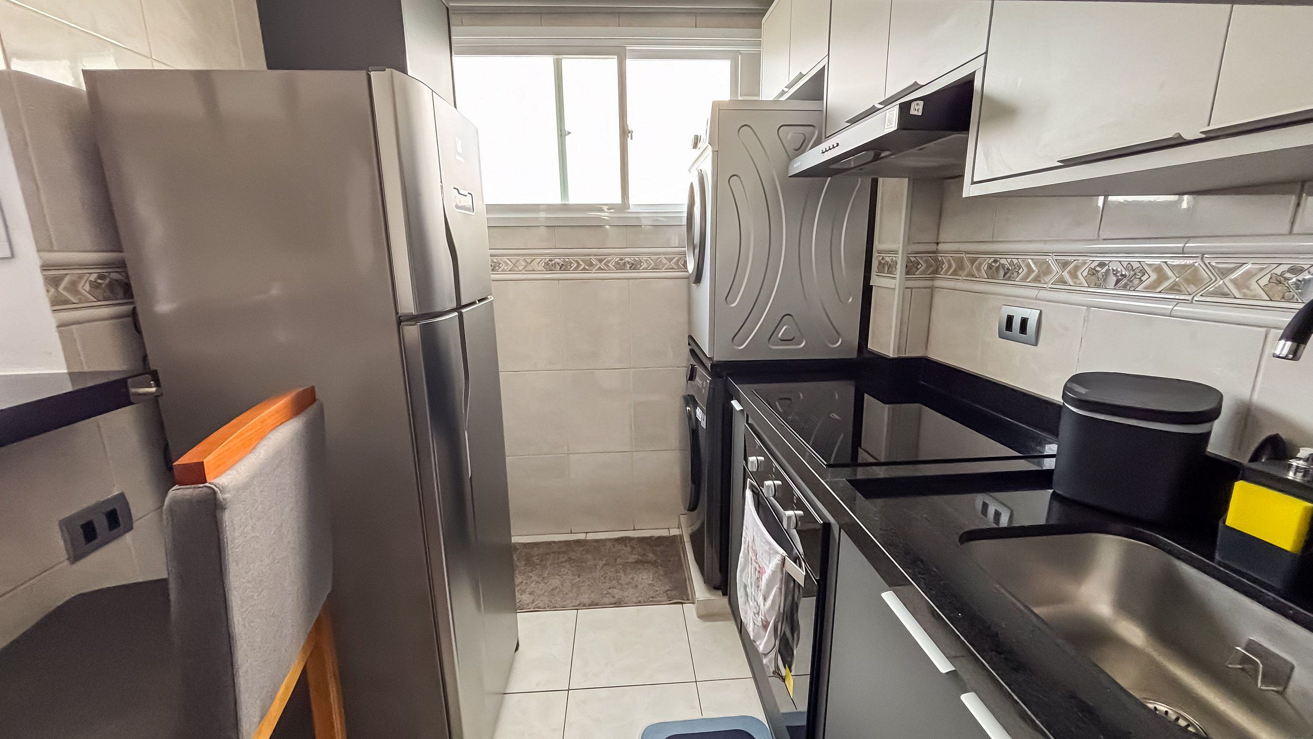 A compact kitchen with a refrigerator, oven, and sink.