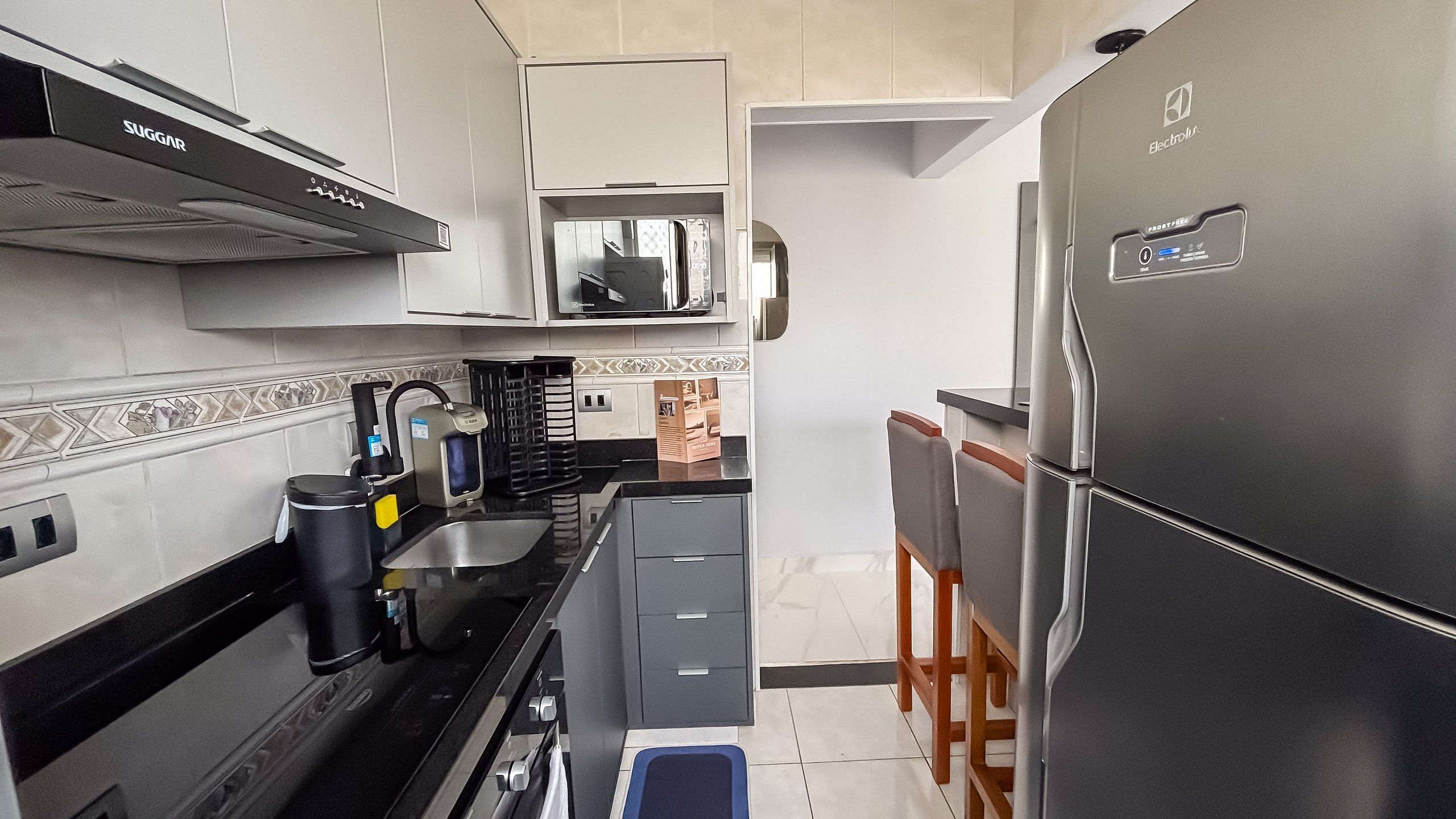 A modern kitchen with a stainless steel refrigerator, a microwave, and a stove. There are cabinets and a sink.