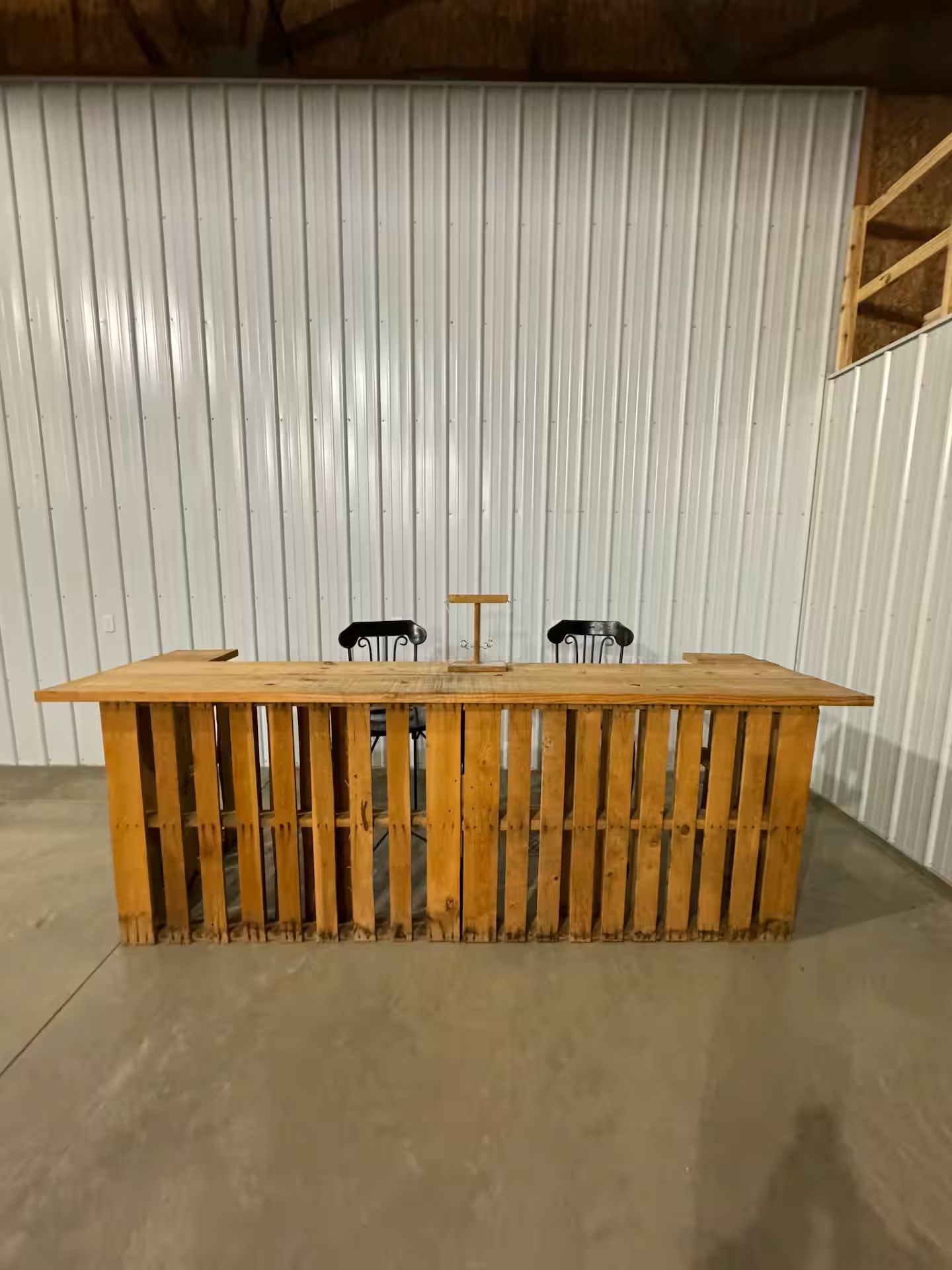 Eine Holztrennwand mit zwei Stühlen davor, vor einer wellenförmigen Metalwand.